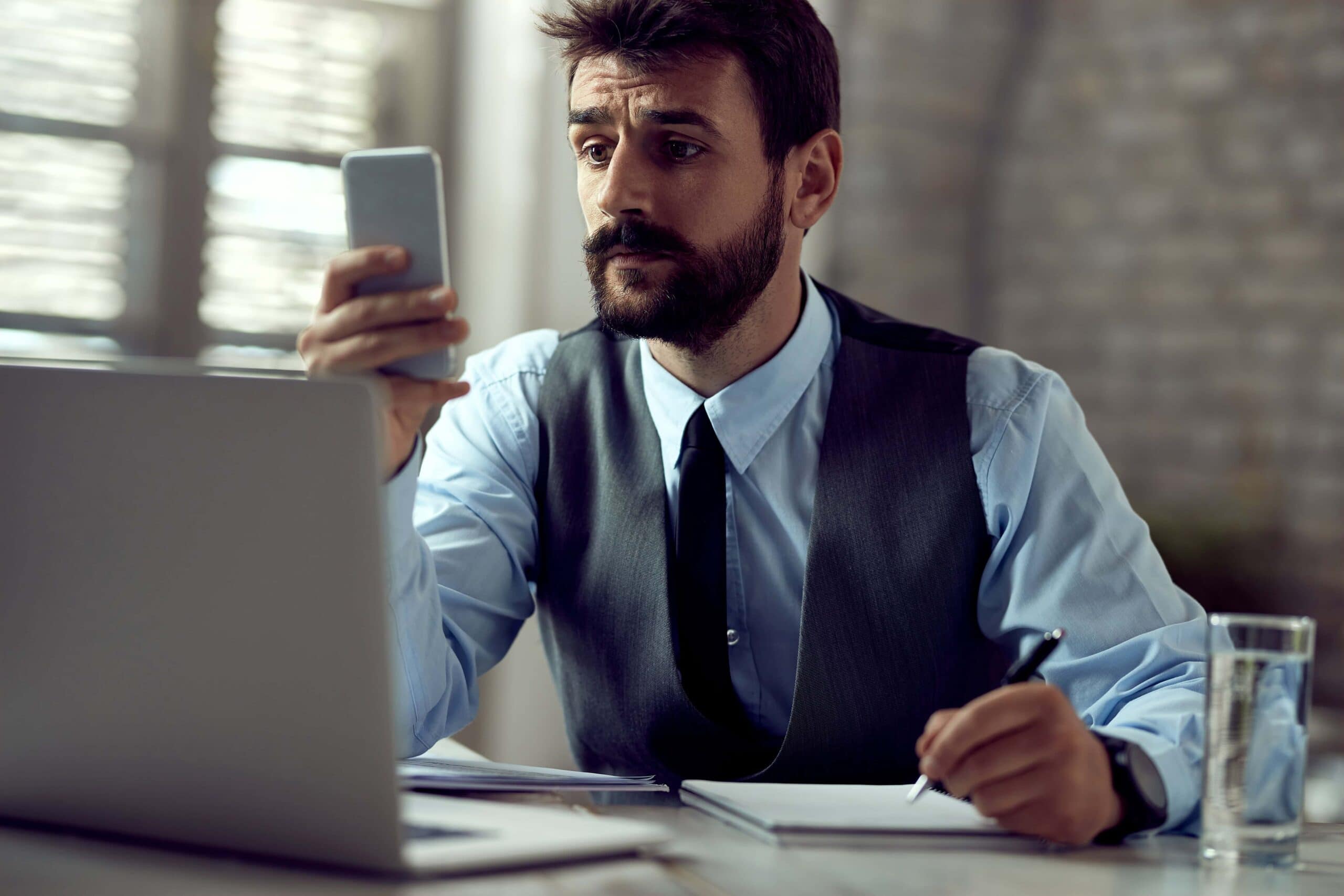 frustrated working man getting distracted by phone